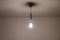 Naked lit light bulb hanging from the ceiling of a dimly lit room