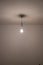 Naked lit light bulb hanging from the ceiling of a dimly lit room