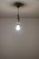 Naked lit light bulb hanging from the ceiling of a dimly lit room