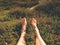 Naked male legs on peak make step. Sandstone rock above valley with tired hikers legs without shoes.