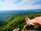 Naked male sweaty legs on peak of rock above valley. The end of trek