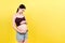 Naked pregnant woman belly wearing opened jeans at colorful background with copy space. Pregnancy concept