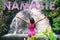 NAMASTE title written as motivational message above yoga girl with open arms meditating at Hawaii waterfall. Wellness