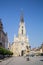 The Name of Mary Church, or Novi Sad catholic cathedral on a sunny afternoon with a crowd walking on Trg Slobode Square.