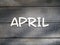 The name of the month is composed of light wooden letters on dark wood. The month of April.
