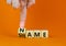 Name or shame symbol. Businessman turns the wooden cube and changes the concept word Shame to Name. Beautiful orange table orange