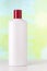 Nameless white plastic bottle for cosmetic product with red cap on a colored background