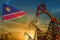 Namibia oil industry concept. Industrial illustration - Namibia flag and oil wells against the blue and yellow sunset sky