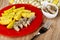 Napkin  bowl with fish  plate with pieces of canned herring and fried potato  fork on table