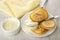 Napkin, bowl with milk, pancake on fork, pancake and spoon with condensed milk in saucer on wooden table