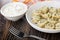 Napkin  bowl with sour cream  plate with dumplings  fork on wooden table