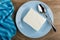 Napkin, briquette of cottage cheese, spoon in blue plate on table. Top view
