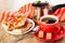 Napkin, cezve, khachapuri with tomato and basil in white plate, cup with coffee, sugar on red saucer, spoon on wooden table