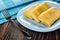 Napkin, fork, fried pancake rolls in blue plate on wooden table
