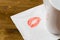 Napkin with a kiss and coffee cup on wooden background