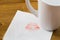 Napkin with a kiss and coffee cup on wooden background