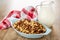 Napkin, pitcher with yogurt, cereal breakfast with chocolate and caramel in blue bowl on wooden table