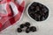 Napkin, prunes in blue bowl, dried plums on wooden table. Top view