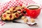 Napkin, shortbread cookies with jam in brown dish, cup of tea, sugar, teaspoon on wooden table