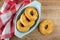 Napkin, shortbread rings in oval plate, cookie on wooden table. Top view