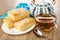 Napkin, teapot, puff pastries in white plate, spoon, transparent cup with tea on wooden table