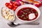 Napkin, tomatoes, salted lard, garlic, borscht with parsley in plate, spoon on table