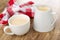 Napkin, white cup and pitcher with fermented baked milk on wooden table