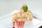 Napoleon cake decorated with a spiral of red chocolate, mint and berry jam on a white plate on a white background