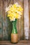 Narcissus flowers in homemade vase on wooden background