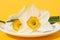 Narcissus flowers lie on a white small plate on a yellow background.