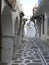 Narrow alley stone pavement with cut trees in Paros island