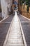Narrow alley with two tracks for car wheels and stairs in the middle, Polop de Marina, Spain