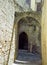 Narrow alleyway in rhodes old town with arches between old stone walls and an open doorway with stairs inside