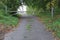 The narrow asphalt road is blocked by a barrier.