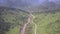 Narrow asphalt road winds along shallow mountain river