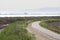 Narrow asphalt walk path turn on a plain coastal landscape