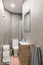 Narrow bathroom with, toilet, small washbasin, decorated with gray tiles. Contemporary style interior after home