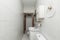 Narrow bathroom with white toilets, mirror
