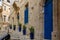 Narrow charming street in Birgu, Malta, with medieval buildings with blue doors, window shutters and plants in