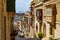 Narrow charming street in Cospicua, Malta, with stairs and traditional wooden balconies