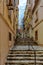 Narrow charming street in Senglea, Malta, with stairs and traditional wooden balconies