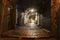 Narrow cobbled street in old medieval town with illuminated houses and pavement. Night shot of side passage in some ancient castle