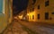 A narrow cobbled street in an old medieval town with lighted houses and antique street lamps. Night shooting