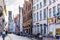 Narrow cobblestone streets and brick houses with step gables and the Belfry Tower in the background in the city of Bruges, Belgium