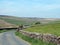 narrow country lane surrounded by dry stone walls in a sunlit rural hilly landscape on the old howarth road in calderdale west