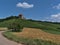 Narrow country road leading through golden barley fields with historic medieval castle Burg Wildeck in Germany.