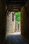 Narrow dark passageway made of ancient stone that leads to medieval house,. Santillana del Mar