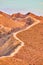 Narrow dirt hiking path follows ridge of mountain top in desert