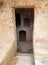 Narrow door carved into rock with steps leading to dark underground chambers at the tombs of the kings in paphos cyprus