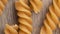 Narrow focus closeup of whole wheat fusilli pasta over wooden table